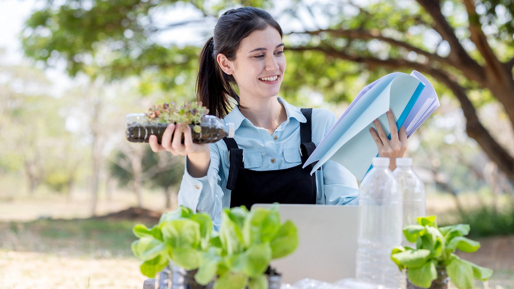 Une gymnasienne souriante plante quelque chose dans une bouteille en plastique