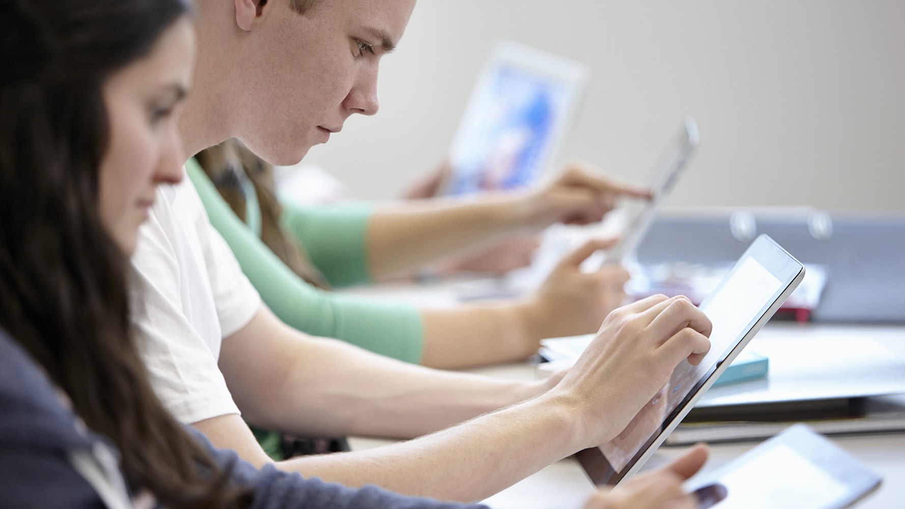 Des jeunes sont assis en classe et travaillent sur des tablettes